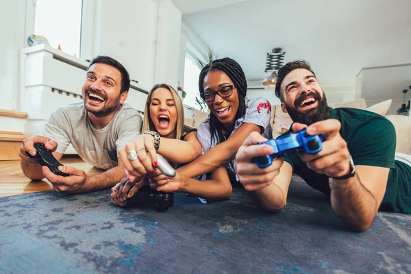 Happy multiethnic friends playing video game and having fun at h