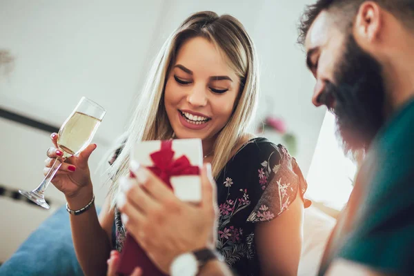 Junger Mann schenkt Frau im Wohnzimmer ein Überraschungsgeschenk — Stockfoto