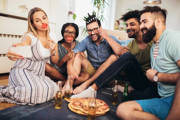 Giovani amici che fanno festa a casa, mangiano pizza e sorridono. — Foto Stock