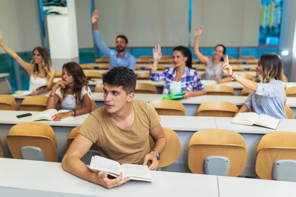 Skupina studentů zvyšování rukou ve třídě na přednášku — Stock fotografie