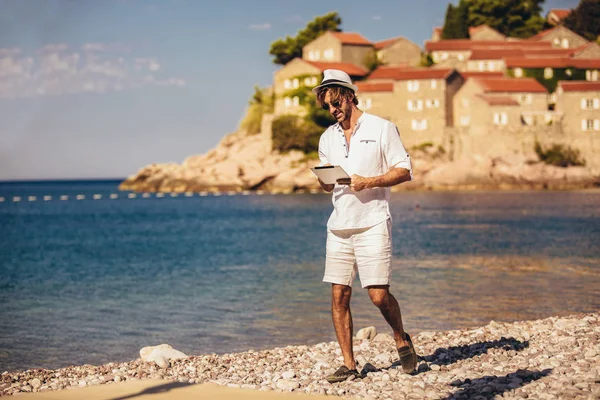 Man ontspannen en gebruik tablet computer op zee strand — Stockfoto