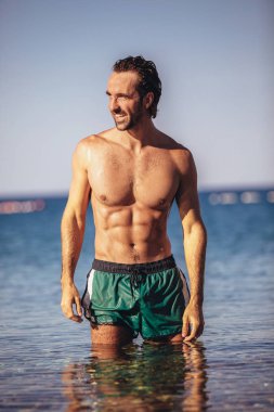 Deniz kenarında poz veren yakışıklı genç adam.