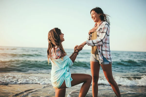 해변에서 행복 한 여자 친구에게 프로 포즈하는 여자 — 스톡 사진