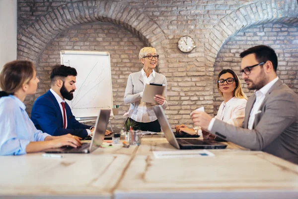 Senior affärskvinna ger presentation för sina kollegor i — Stockfoto