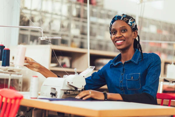 Joven trabajador textil africano cosiendo en línea de producción . — Foto de Stock