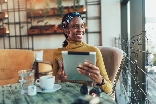 Glad ung kvinna sitter på café håller digital tablett och cre — Stockfoto