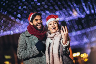 Mutlu, genç, sevgi dolu bir çift selfie çekiyor ve gülümsüyor.