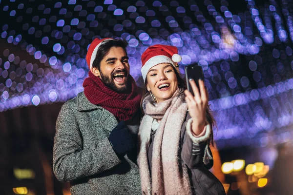 Glada unga kärleksfulla par gör selfie och leende medan standi — Stockfoto