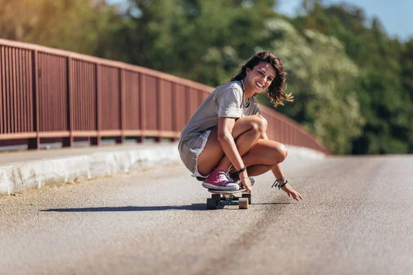 Jonge sportieve vrouw rijden op het skateboard op de weg. — Stockfoto