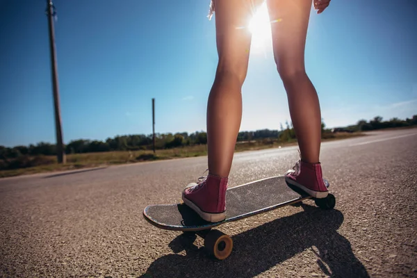 Close up de pés de uma menina de tênis vermelho montando no skatebo — Fotografia de Stock