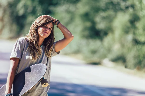 Skateboard meisje liften en stoppen auto op het platteland weg — Stockfoto