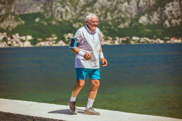 Gelukkig senior man doen ochtend oefening op het strand — Stockfoto