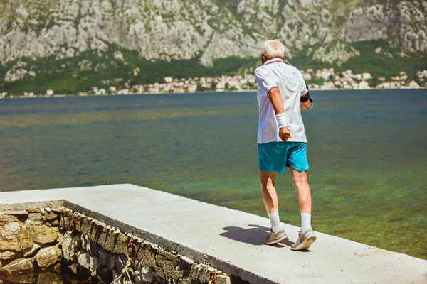 Gelukkig senior man doen ochtend oefening op het strand — Stockfoto