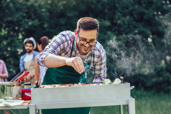 Jonge knappe man bereidt barbecue voor vrienden. — Stockfoto