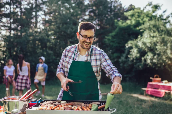Young handsome man preparing barbecue for friends. — Stock Photo, Image