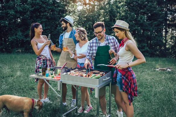 Tineri prieteni având distracție gratar carne se bucură de grătar petrecere . — Fotografie, imagine de stoc