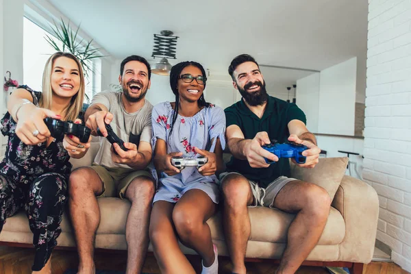 Felices amigos multiétnicos jugando videojuegos y divirtiéndose en h —  Fotos de Stock