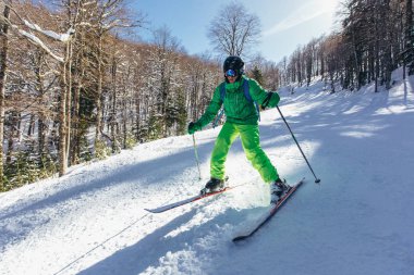 Yüksek dağlarda güneşli bir günde kayak yapan kayakçı. 