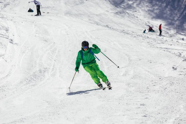 Esquiador esquiando cuesta abajo durante el día soleado en las altas montañas — Foto de Stock