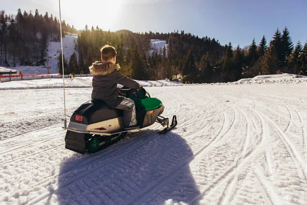 Niño conduciendo moto de nieve en un paisaje de invierno — Foto de Stock