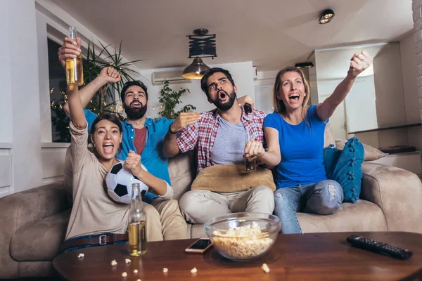 Bir grup neşeli arkadaş futbol maçı izleyip kutluyorlar. 