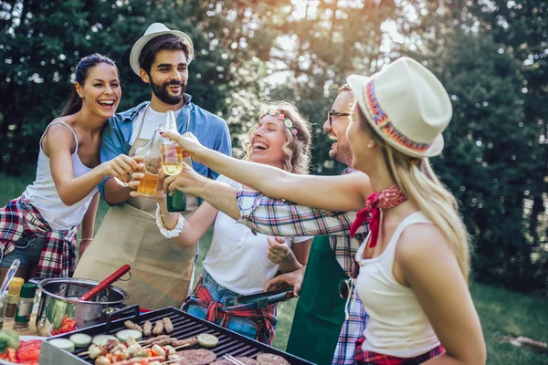 Grupa przyjaciół stoją na grillu, jeden gotowanie na grillu — Zdjęcie stockowe