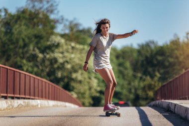 Sportif bir kadın yolda kaykaya biniyor. Uzatma tahtası,
