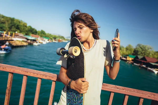 Mulher bonita e moda jovem posando com um skate — Fotografia de Stock