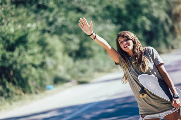 Skateboard meisje liften en stoppen van de auto met duimen up gest — Stockfoto