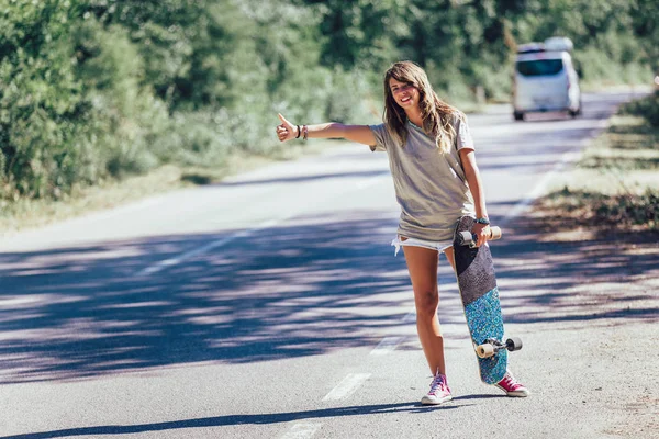 Skateboard meisje liften en stoppen van de auto met duimen up gest — Stockfoto