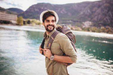 Genç bir adam B ile turistik bir tatil köyünün limanında yürüyor.