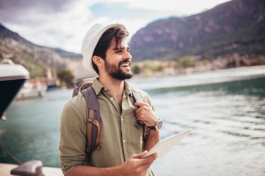 Genç bir adam B ile turistik bir tatil köyünün limanında yürüyor.