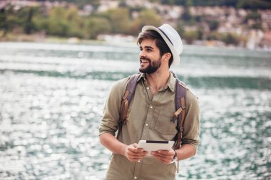 Genç bir adam B ile turistik bir tatil köyünün limanında yürüyor.