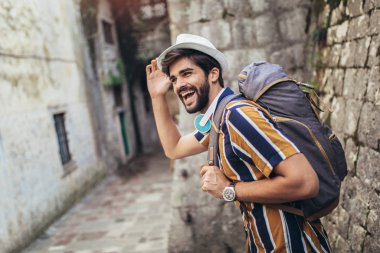 Sırt çantalı yakışıklı sakallı turist C boyunca seyahat ediyor.