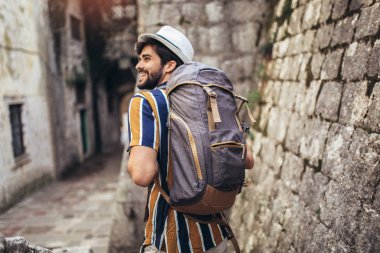 Sırt çantalı yakışıklı sakallı turist C boyunca seyahat ediyor.