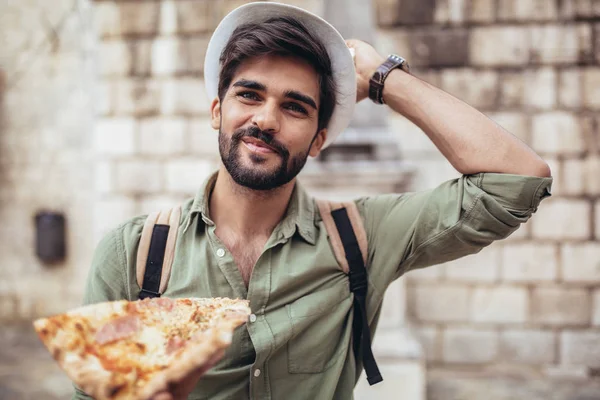 Glücklicher Mann isst Pizza auf der Straße. — Stockfoto