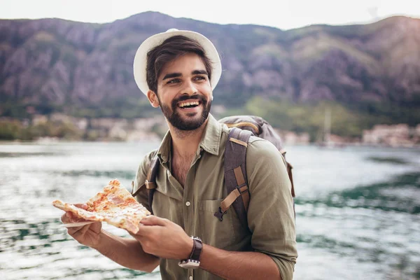 Happy tourist man eating pizza.