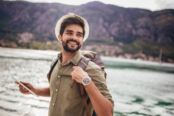 Jeune homme marchant près du port d'une station balnéaire touristique avec — Photo