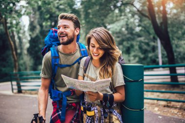 Doğal arka plan üzerinde sırt çantaları ile yürüyen gülümseyen çift