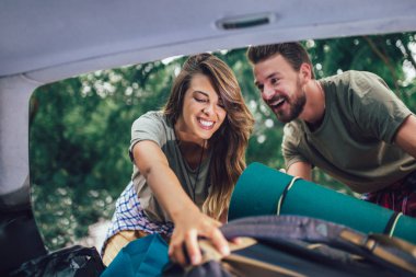 Genç çift kamp malzemelerini yerleştirirken eğleniyor.