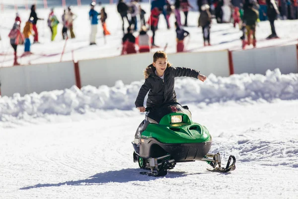 Menino dirigindo snowmobile em uma paisagem de inverno — Fotografia de Stock