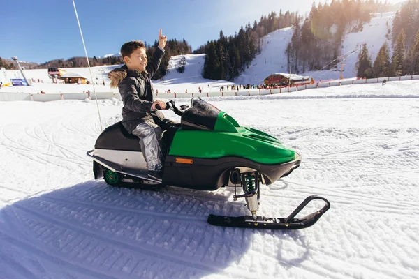 Niño conduciendo moto de nieve en un paisaje de invierno —  Fotos de Stock