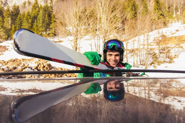 Esquiador macho sujetando esquís a los raíles del techo del coche —  Fotos de Stock