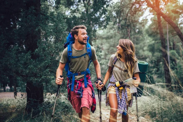 Coppia sorridente che cammina con zaini su sfondo naturale — Foto Stock