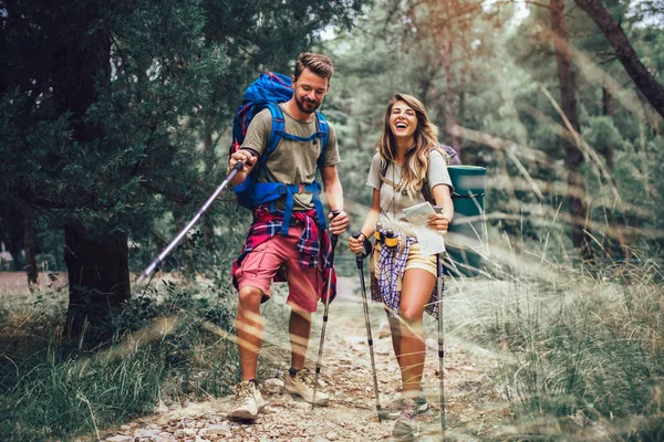 Coppia sorridente che cammina con zaini su sfondo naturale — Foto Stock