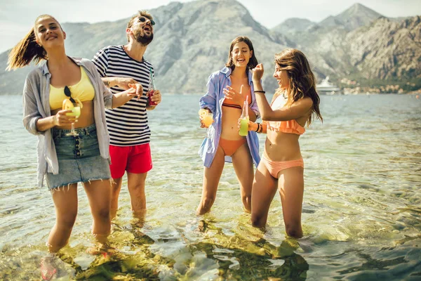 Летняя вечеринка. Друзья на пляже пьют коктейли, веселятся — стоковое фото