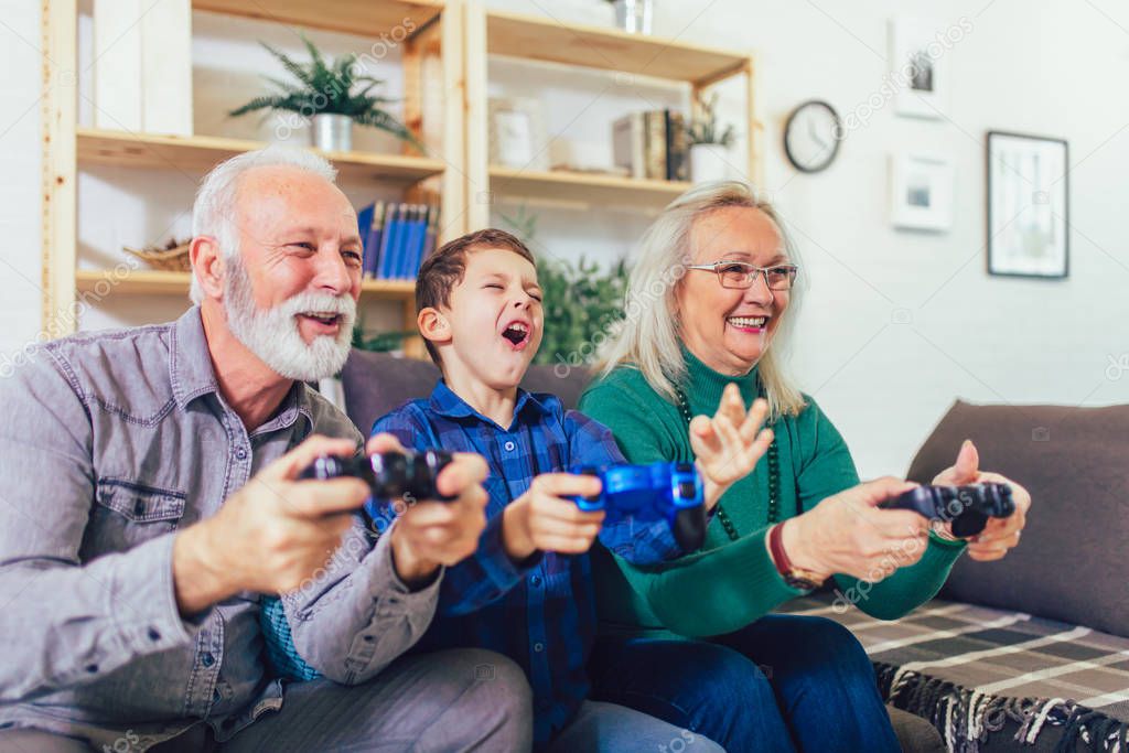 Senior man and woman play video games while their grand