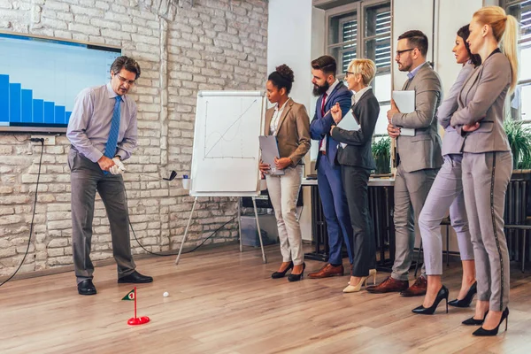 Respectable elderly man in a business suit playing mini-golf in — 스톡 사진