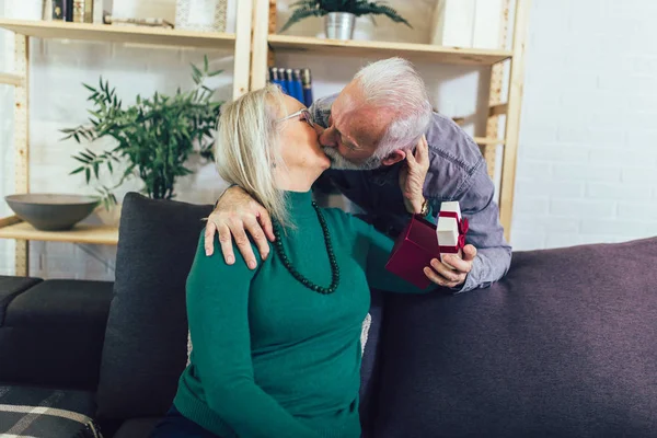 Idősebb férfi ajándékot ad a nőjének otthon.. — Stock Fotó