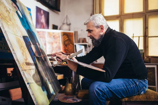 Dojrzałe mężczyzna malarstwo na płótnie w studio sztuki. — Zdjęcie stockowe